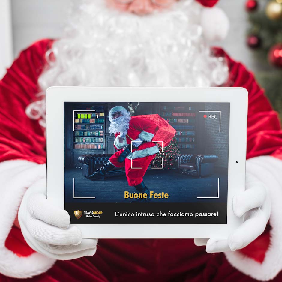 Grafica di auguri Unisecur su un tablet tenuto da Babbo Natale