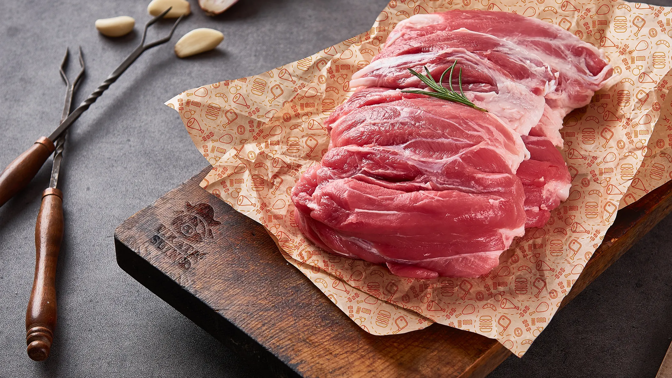 Carne fresca avvolta nella carta da macelleria personalizzata Pirata Suino su un tagliere marchiato