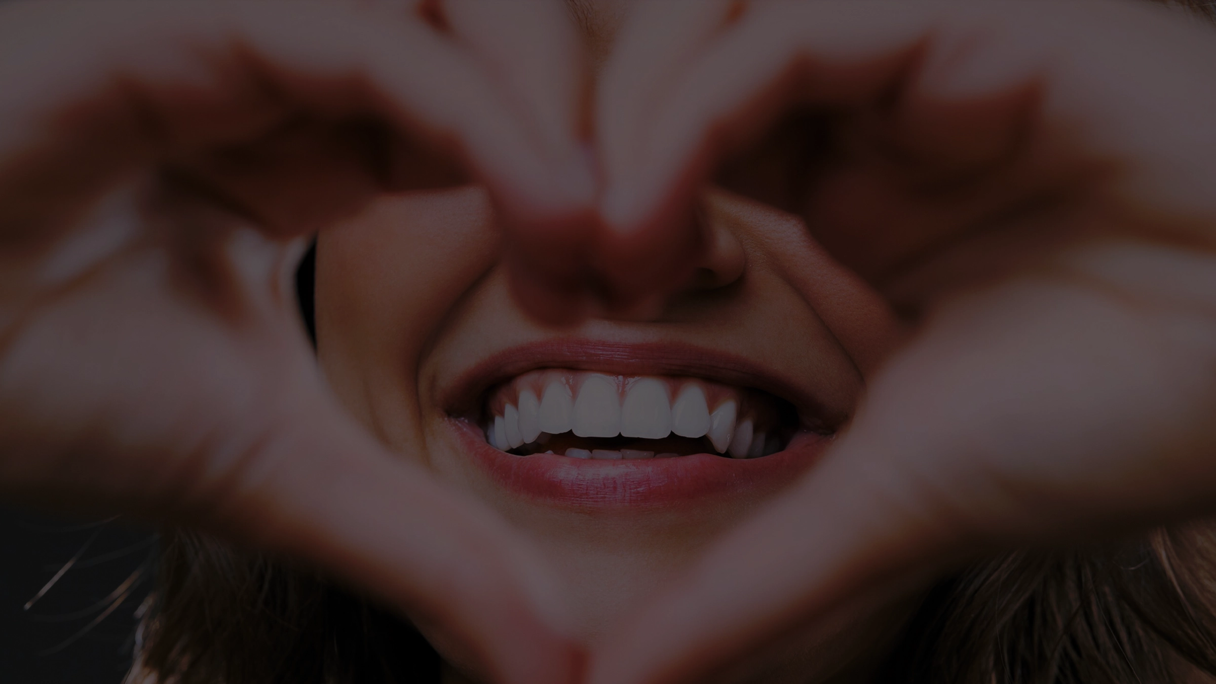Sorriso incorniciato da due mani a forma di cuore